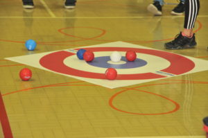 Red and blue boccia balls sit on a target mat during a game.