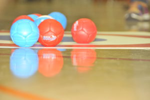 A set of blue and red boccia balls sit on the target