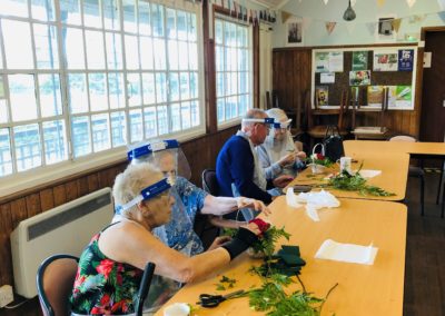 Four members of the Elderflower Hub sit at a table and make floristry baskets