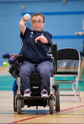 Evie Edwards, Paralympian, holds a ball in her right hand and aims a shot during a Boccia game at an ActivLives session.