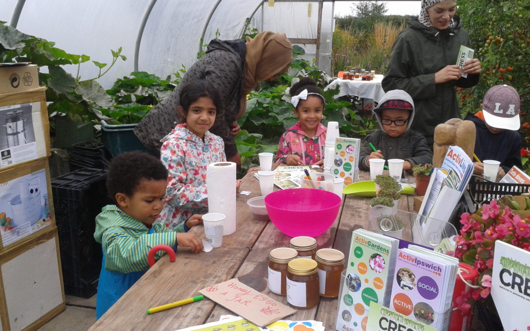 A group of adults and children enjoy planting seeds at the people's community garden