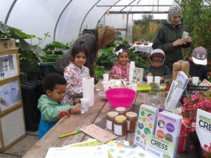 A group of adults and children enjoy planting seeds at the people's community garden