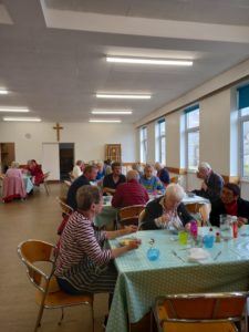 ActivLives lunch club. People sit at several tables dotted around the room, all are eating their lunch and having a chat.