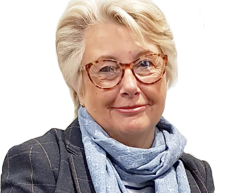 A head and shoulders image of councillor Mary Rudd, she wears a grey jacket, blue scarf and wears brown glasses. She has her shoulder length hair swept back.