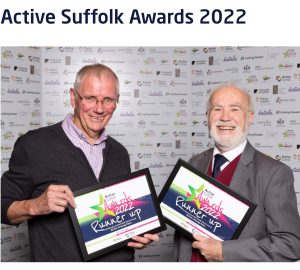 2 men smile at the camera and hold their runner sup certificates from the awards ceremony at the active Suffolk awards night.