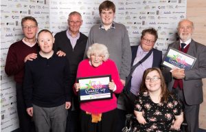 A group of people all stand together and have a photo taken, they all smile at the camera and hold up their runners up certificates that they received at the active Suffolk awards ceremony.