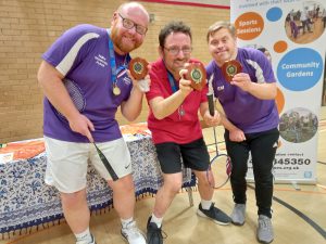 Three badminton players show off their winners medals and trophies at the recent badminton tournament.