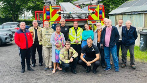A group of men stand in front of a fire engine and they all smile at the camera. This was a visit organised for the Men’s Breakfast Hub.