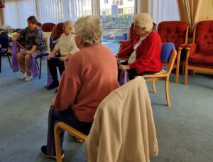 A group of women doing a seated exercise inside a hall