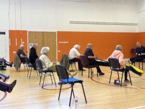 A group of participants doing an exercise with an instructor inside a sports hall