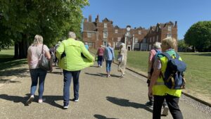 A group of volunteers and participants walking inside the park in front of a mansion.