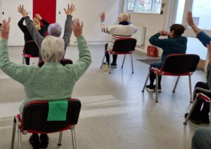 Group of ladies doing seated exercise inside a hall